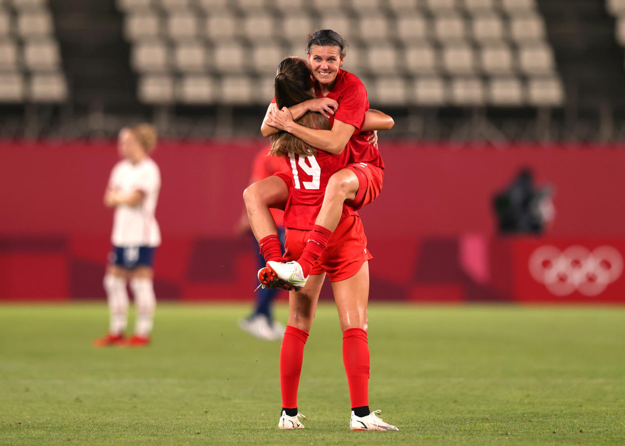 KASHIMA, JAPAN - AUGUST 02: Christine Sinclair #12 of Team Canada jumps on team mate Jordyn Huitema #19 of Team Canada following their side's victory in the Women's Semi-Final match between USA and Canada on day ten of the Tokyo Olympic Games at Kashima Stadium on August 02, 2021 in Kashima, Ibaraki, Japan. (Photo by Naomi Baker/Getty Images)