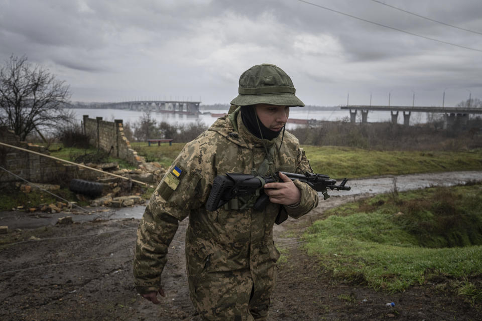 A Ukrainian serviceman patrols area near the Antonovsky Bridge which was destroyed by Russian forces after withdrawing from Kherson, Ukraine, Thursday, Dec. 8, 2022. (AP Photo/Evgeniy Maloletka)