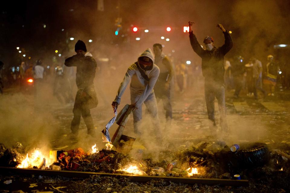 Demonstrators block a street with a burning barricade in the Altamira neighborhood of Caracas, Venezuela, Wednesday, Feb. 19, 2014. Venezuelan security forces backed by water tanks and tear gas dispersed groups of anti-government demonstrators who tried to block Caracas' main highway Wednesday evening. (AP Photo/Rodrigo Abd)