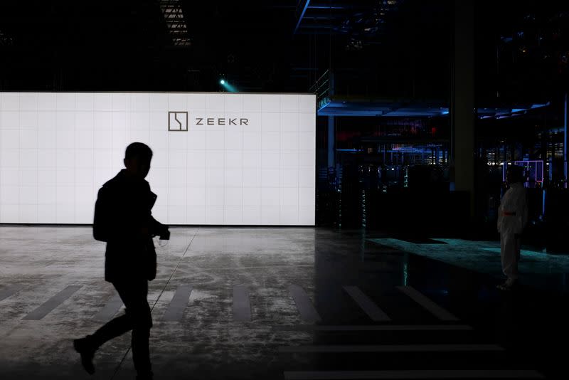 Man walks past a sign of Geely's new brand Zeekr at its factory in Ningbo