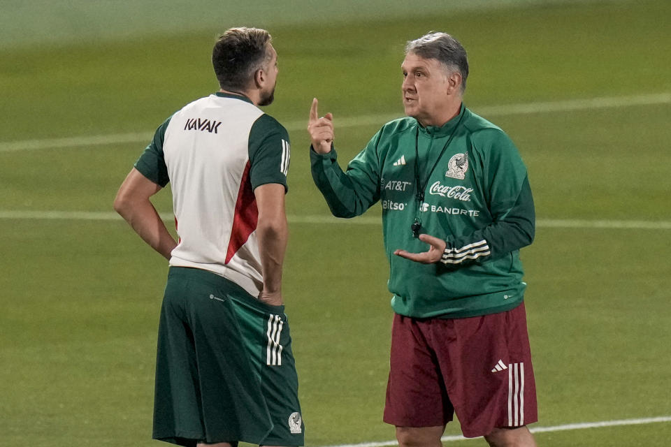 Mexico's head coach Gerardo Martino, right talks with Hector Herrera during a training session in Jor, Qatar, Wednesday, Nov. 23, 2022. (AP Photo/Moises Castillo)