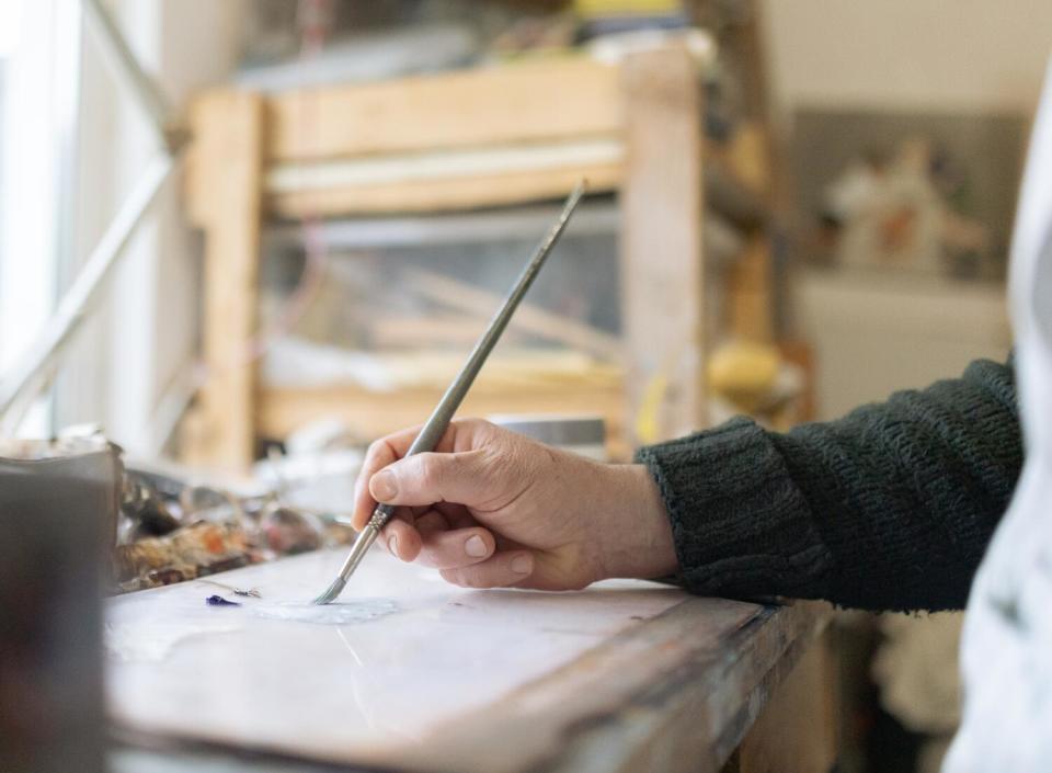 A close view of a man's hand holding a paintbrush.