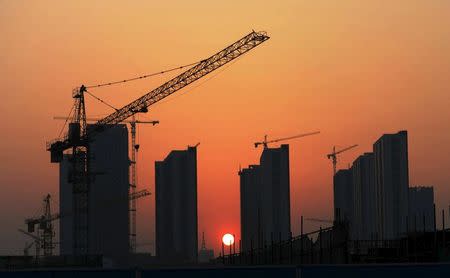 The sun sets behind a residential construction site in Rizhao, Shandong province April 14, 2015. REUTERS/Stringer