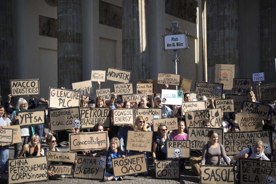 Manifestantes exhiben letreros de empresas que usan o lidian con energía fósil durante una protesta climatológica global del movimiento "Fridays For Future" en Berlín, Alemania, el viernes 15 de septiembre de 2023. (AP Foto/Markus Schreiber)