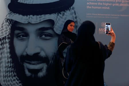 FILE PHOTO: Participants take photos next to a picture of Saudi Crown Prince Mohammed bin Salman during the Misk Global Forum in Riyadh