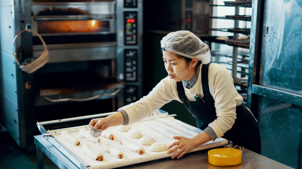 Mid adult woman baking bread in an industrial kitchen in Japan.