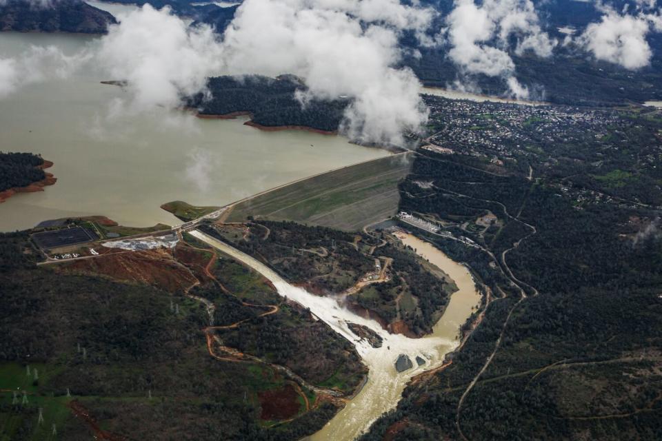 Water flows out of a spillway near a dam.