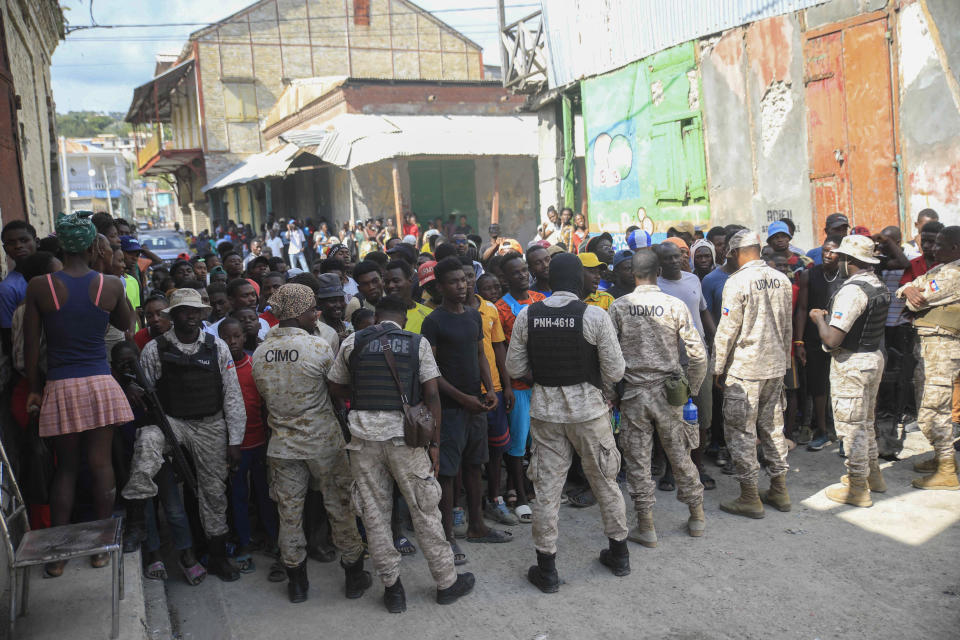 Police officers block persons as they protest against the arrival of the USNS Comfort hospital ship in Jeremie, Haiti, Tuesday, Dec. 13, 2022. The USNS Comfort is on a humanitarian mission to provide dental and medical services. (AP Photo/Odelyn Joseph)