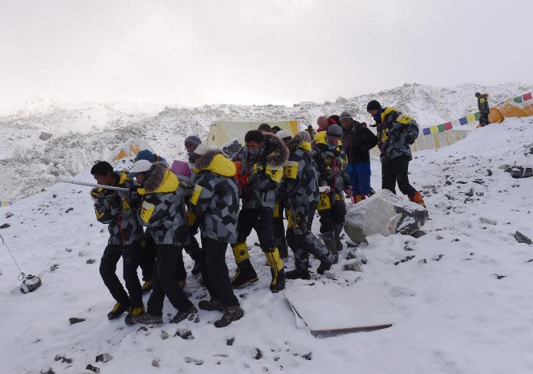 An injured person is carried by rescue members to be airlifted at Everest Base Camp on April 26, 2015, a day after an avalanche triggered by an earthquake devastated the camp