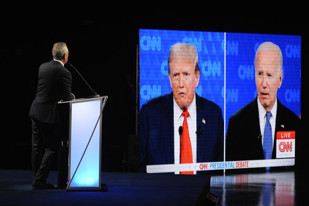 Presidential candidate Robert F. Kennedy Jr. stands onstage at a campaign event watching a live feed of the presidential debate.