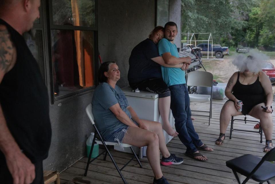 Miranda Michel embraces her partner, Levi Langley, as they and their family enjoy the porch.