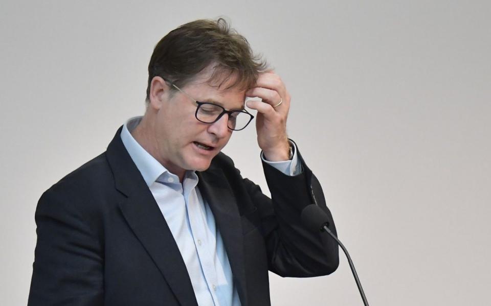 Sir Nick Clegg, an ageing white man with tousled brown hair and thick black-rimmed glasses, wearing a suit with no tie, holds his head for a moment as if searching for words while he stands behind a lectern - Tobias Schwarz/AFP/Getty