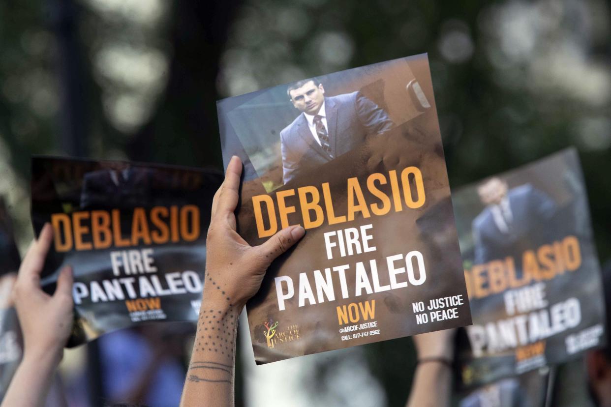 Demonstrators holding signs while calling on New York Mayor Bill de Blasio to fire police officer Daniel Pantaleo during a rally outside New York Police Department headquarters in Manhattan, New York.