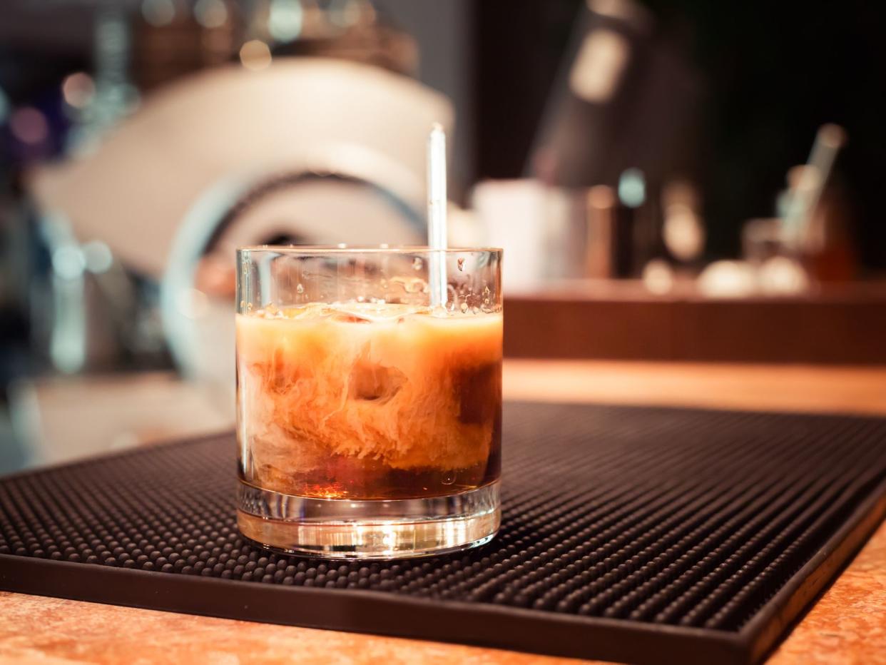 White russian cocktail on the bar stand on rubber mat. Shallow DOF and marsala tonned