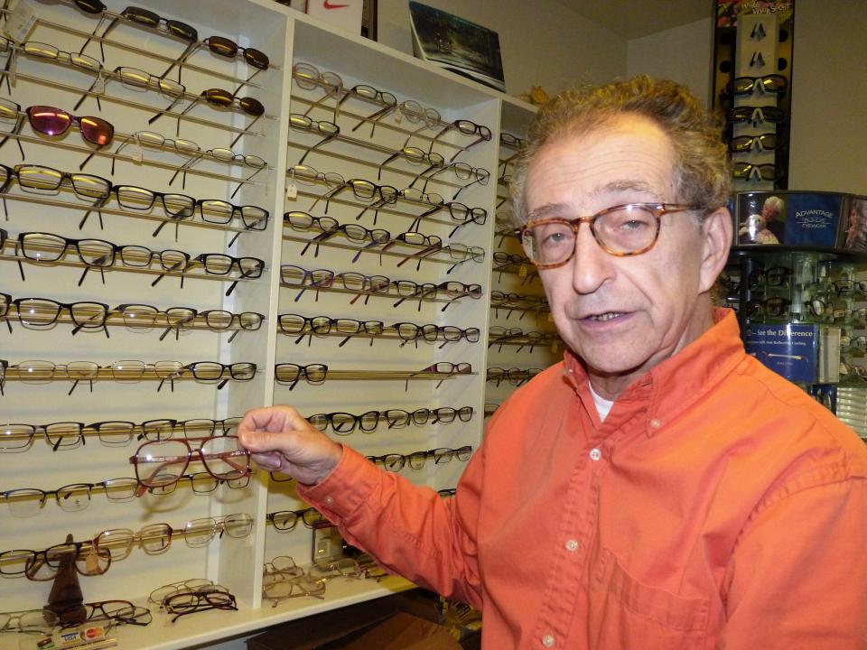 David Weininger in front of a wall of glasses at his New Brunswick optometry office.