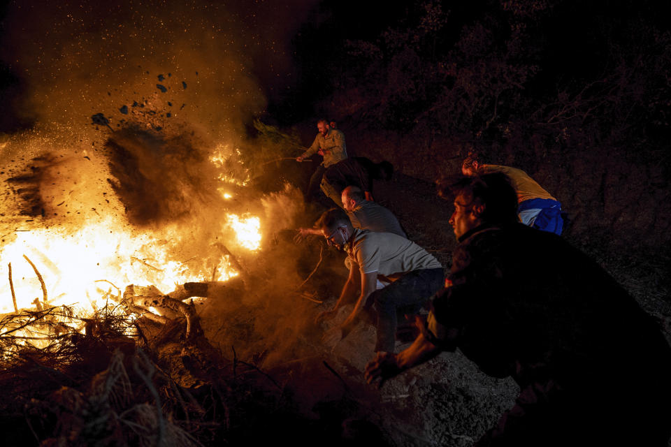 Firefighters and residents try to extinguish a fire in the city of Canakkale, northwest Turkey, Wednesday, Aug. 23, 2023. Authorities evacuated three villages and temporarily closed down a highway as firefighters battled a wildfire, fanned by strong winds, in northwestern Canakkale province. (Ugur Yildirim/dia images via AP)