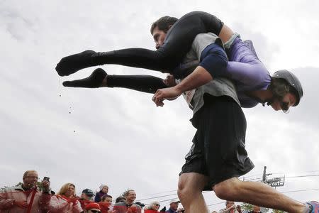 Nathan Johnson carries Tia Johnson out of the water pit while competing in the North American Wife Carrying Championship at Sunday River ski resort in Newry, Maine October 11, 2014. REUTERS/Brian Snyder