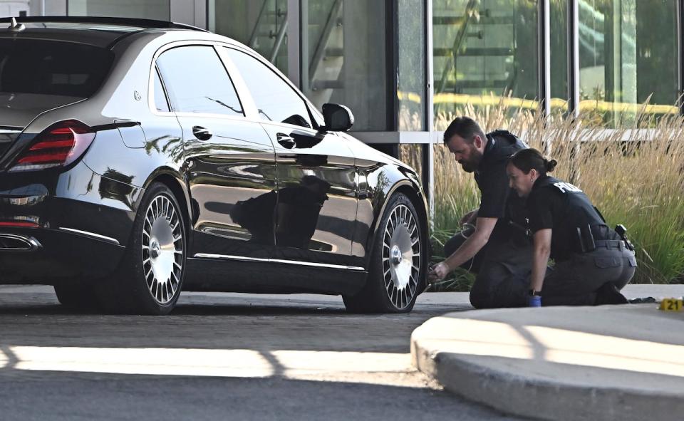 Ottawa police officers examine the front end of a sedan on Sept. 3, 2023 as they collect evidence after a shooting that left two people dead.