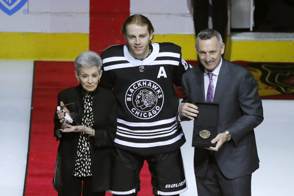 Chicago Blackhawks' Patrick Kane, center, stands with Jill Mikita, left, and Denis Savard as he is honored for his 1000th point before an NHL hockey game between the Blackhawks and Florida Panthers Tuesday, Jan. 21, 2020, in Chicago. (AP Photo/Charles Rex Arbogast)