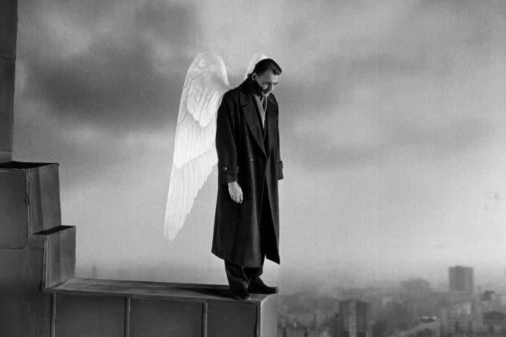 An angel on the edge of a building looking down in Wings of Desire.