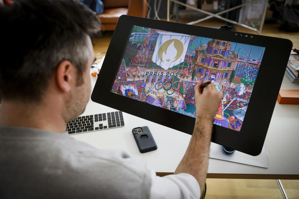 CORRECTS SPELLING OF FIRST NAME FROM HUGO TO UGO - French artist Ugo Gattoni works on the Paris 2024 Olympic and Paralympic posters at his workshop, in Ivry-sur-Seine, outside Paris, Tuesday Feb.20, 2024. Vibrant colors and striking landmarks illuminate posters for the Paris Olympic Games in an Art Deco style inspired by the city's flamboyant past. The posters have been unveiled at the Musée d'Orsay. (AP Photo/Thomas Padilla)