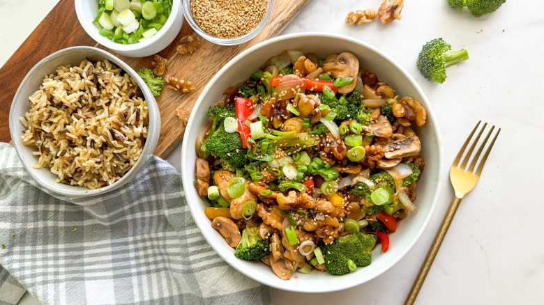 bowl of veggie stir fry with walnuts and side of rice