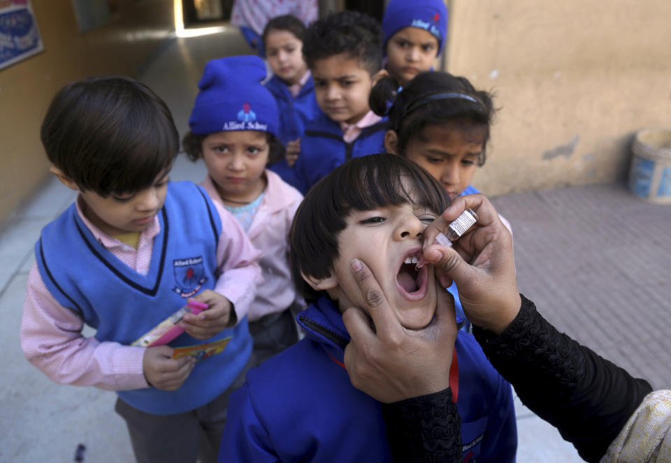 A health worker gives a polio vaccine to a child at a school in Lahore, Pakistan, Monday, Feb. 17, 2020. Pakistan government launched an anti-polio vaccination campaign in an effort to eradicate the crippling disease affected children. (AP Photo/K.M. Chaudary)