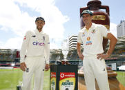 England captain Joe Root, left, and Australian captain Pat Cummins pose with the Ashes trophy at the Gabba cricket ground ahead of the first Ashes cricket test in Brisbane, Australia, Sunday, Dec. 5, 2021. (AP Photo/Tertius Pickard)
