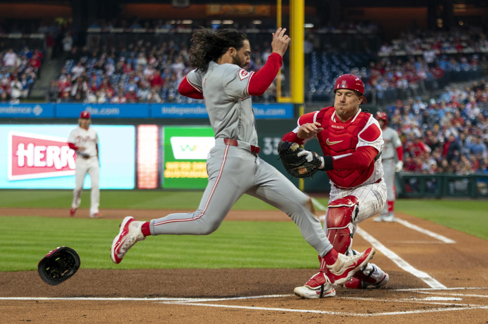 Philadelphia Phillies catcher J.T. Realmuto, right, looks to tag out Cincinnati Reds' Jonathan India, left, during the first inning of a baseball game, Monday, April 1, 2024, in Philadelphia. (AP Photo/Chris Szagola)
