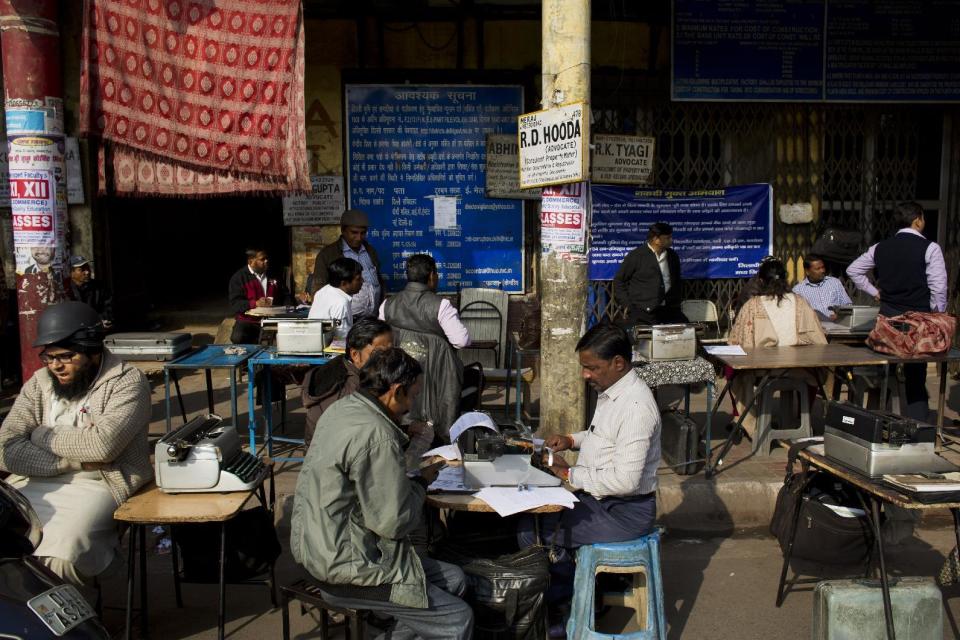 In this Jan. 18, 2017 photo, professional typists work on a roadside near Delhi's stock exchange market in New Delhi, India. India is one of the last places in the world where the typewriter continues to cling to life. This country has thousands of professional typists, most of them working outside the country's courts and government offices. But even in India, where stodgy government bureaucracies have helped the typewriter survive, its twilight is at hand.(AP Photo/Bernat Armangue)