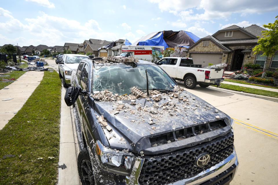 A truck is covered in debris as families in Bridgeland begin to clean up storm damage, Sunday, May 19, 2024, in Cypress, Texas. (Brett Coomer/Houston Chronicle via AP)