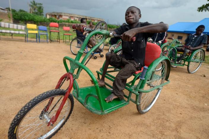 Handicapped Jacob Clement rides on his new wheelchair at the Beautiful Gate Handicapped People's Centre in Jos, northcentral Nigeria Plateau State, on July 16, 2015 (AFP Photo/Pius Utomi Ekpei)