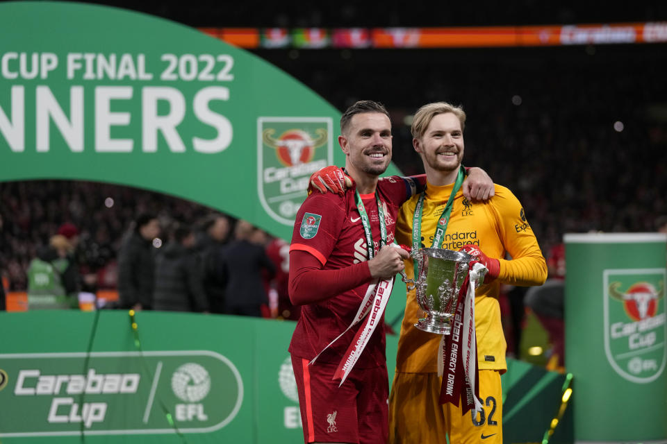Liverpool's Jordan Henderson and goalkeeper Caoimhin Kelleher, right, pose with the trophy after winning the English League Cup final soccer match between Chelsea and Liverpool at Wembley stadium in London, Sunday, Feb. 27, 2022. Liverpool won a penalty shootout 11-10 after the match ended tied 0-0. (AP Photo/Alastair Grant)