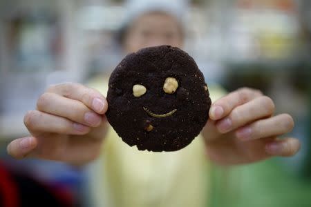 A sales assistant poses for photographs with a mealworm cookie in Seoul, South Korea, August 8, 2016. Picture taken August 8, 2016. REUTERS/Kim Hong-Ji