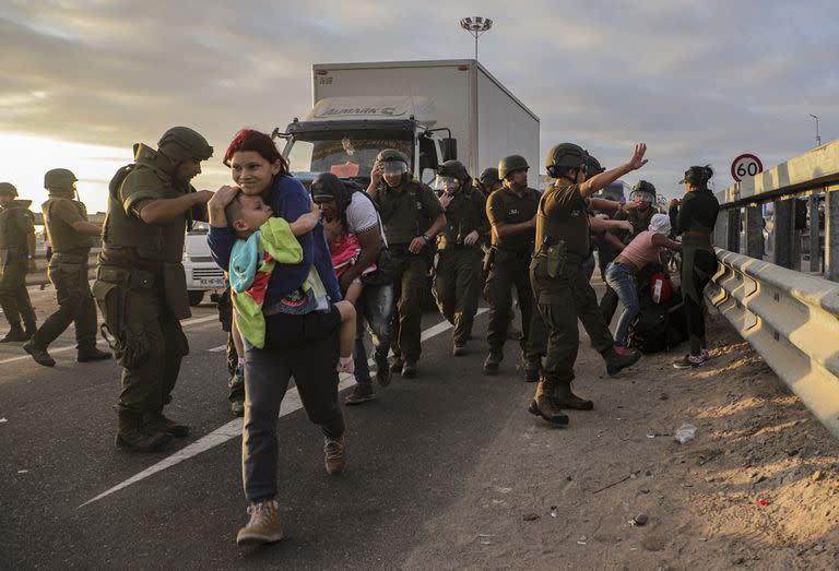 Migrantes que bloquean la carretera en la frontera entre Chile y Perú son dispersados por la policía chilena cerca de Arica, Chile, el martes 2 de mayo de 2023.