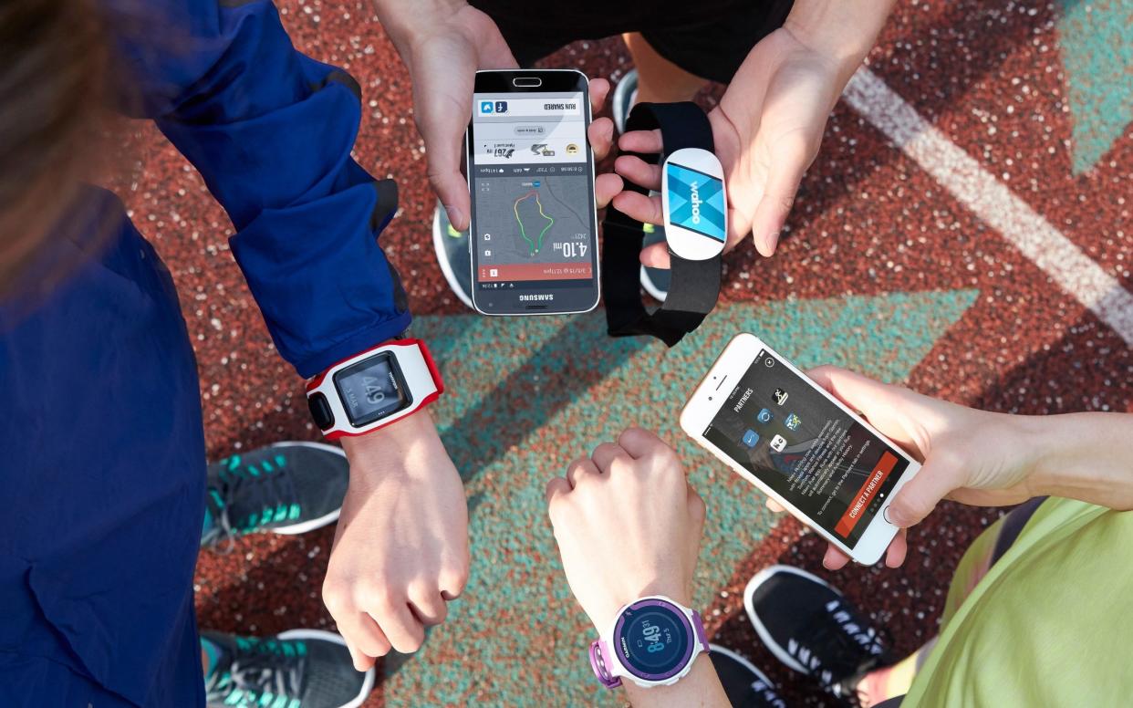 A stock photo of a group of runners using phones and watches to track their routes