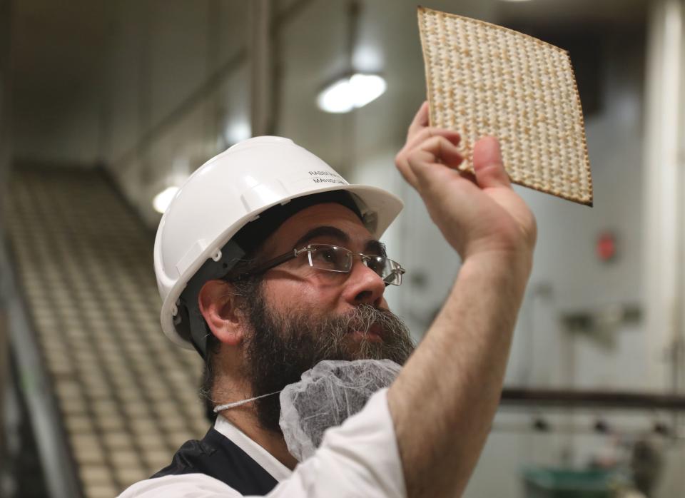 Rabbi Aron Hayum, plant manager at Manischewitz in Newark, N.J. looking over a matzo that just came out of the oven. Rabbis on the production line check to make sure matzos have been made following kosher guidelines