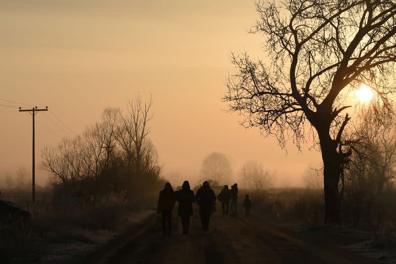 Migrants walk on a dirt road at dawn, after crossing from Turkey into Greece, near the town of Orestiada