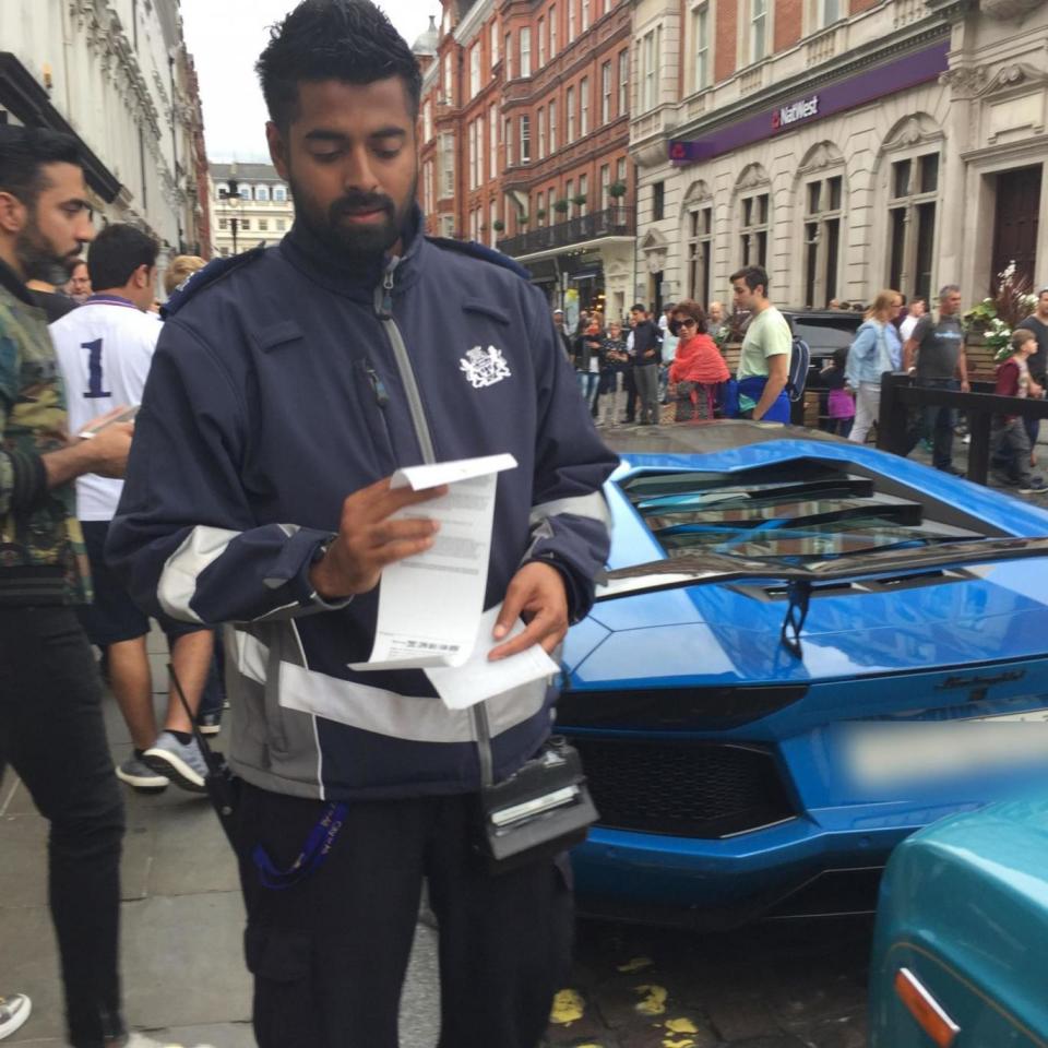 A traffic warden issuing parking fines for the supercars.