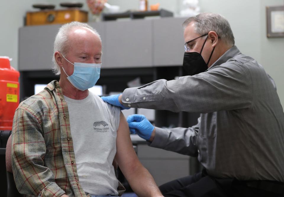 Ken Dunn, 70, receives his booster from pharmacist Tom Lamb at Sand Run Pharmacy on Thursday.