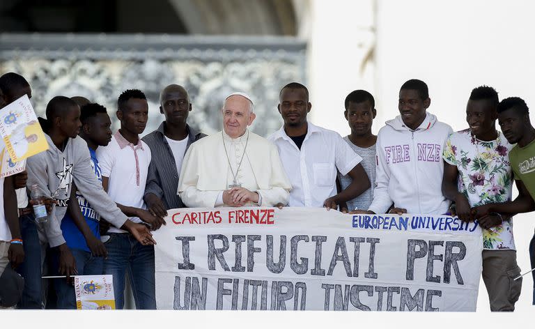 En esta imagen de archivo, el papa Francisco posa para una fotografía con un grupo de refugiados a los que invitó a las escaleras de la Basílica de San Pedro, con una bandera con la frase (en italiano) 