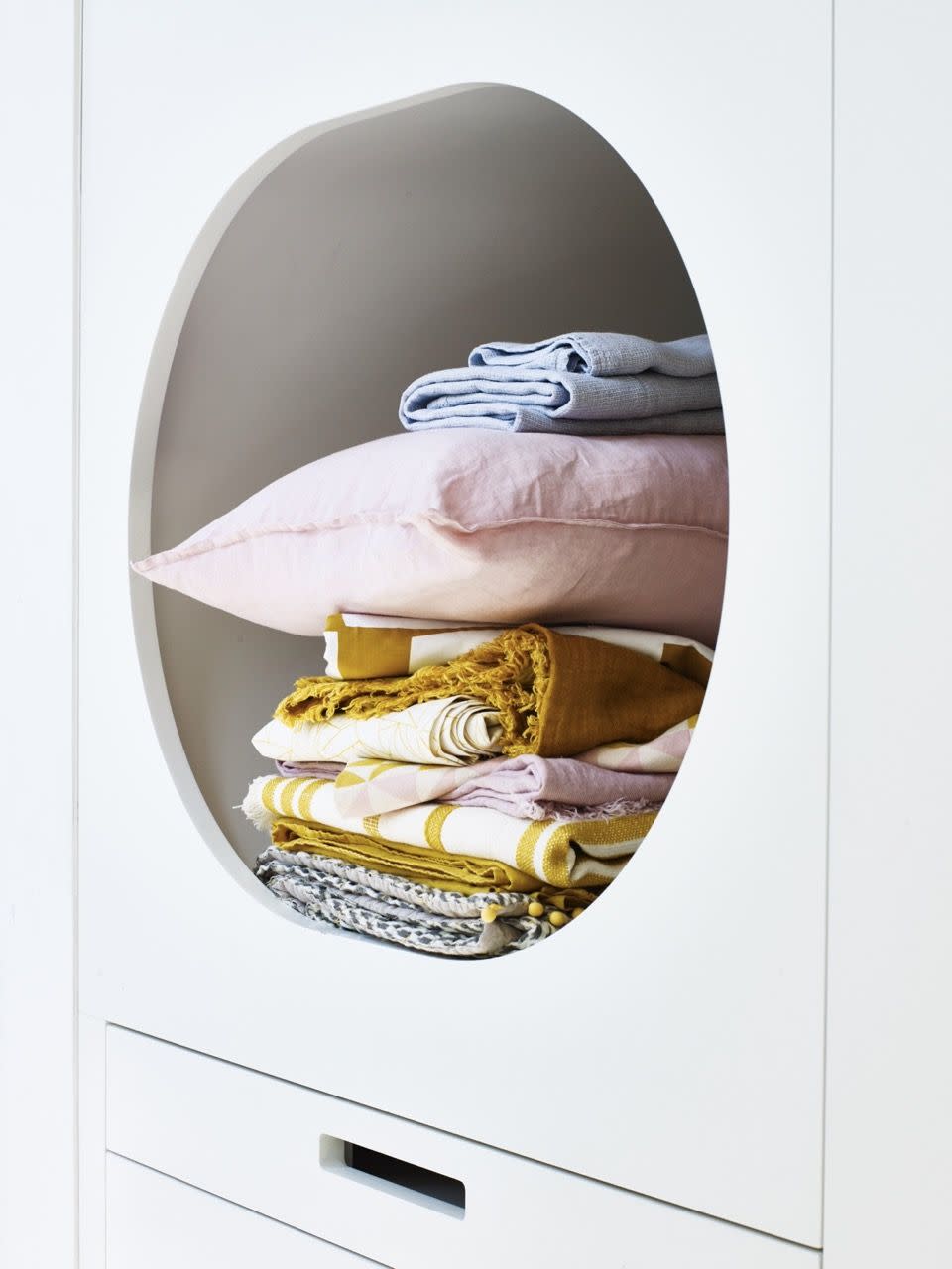 golden ochre home accessorieslayering linens with different weaves and textures introduces a tactile element to bedroom storage, circular opening in white cupboard