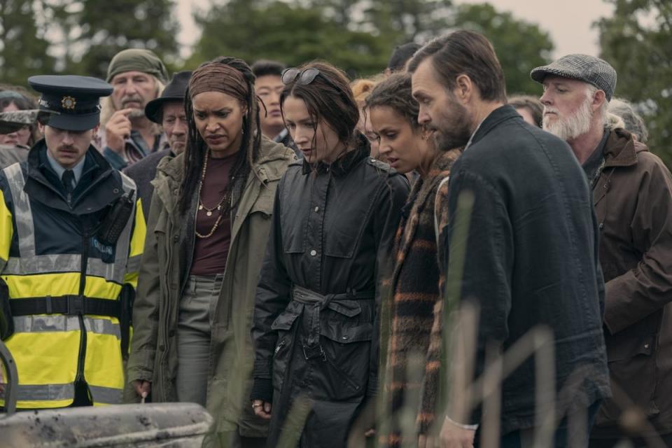 A group of people outside looking down at the ground on Bodkin