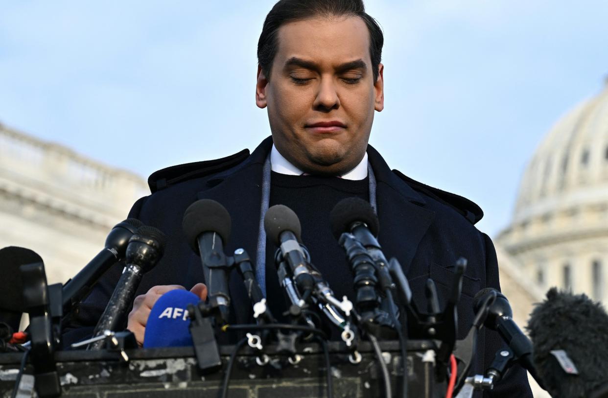 George Santos looks down at a bank of microphones during a press conference on Capitol Hill.