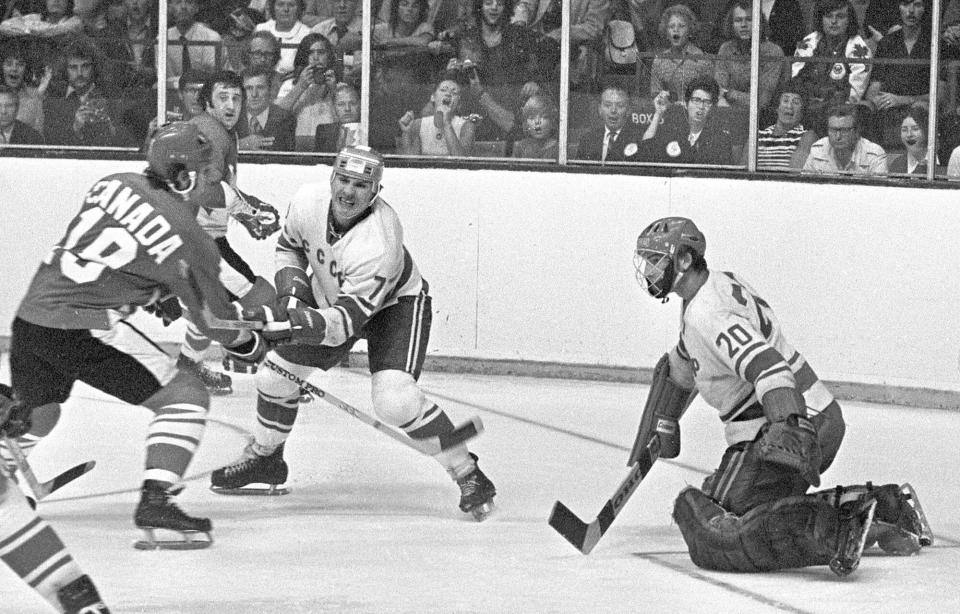 FILE - Team Canada's Paul Henderson, left, shoots against Team USSR's Vladislav Tretiak as Gannady Tsygankov defends during the Summit hockey tournament in Toronto, Sept. 4, 1972. Henderson, a former NHLer who will always be remembered for scoring the decisive goal in clinching Canada its Summit Series win over Russia some 50 years ago, will get more recognition on Saturday, when he'll celebrate his 80th birthday with a ceremonial puck drop before Cansius' game against Niagara. Henderson's grandson, Alton McDermott, is a left wing for Canisius. (AP Photo/The Canadian Press, Peter Bregg, File)