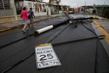 People walk next to fallen electric poles and traffic sings after the area was hit by Hurricane Maria in Salinas, Puerto Rico, September 21, 2017. REUTERS/Carlos Garcia Rawlins