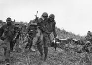 <p>11th April 1968: US soldiers, one wounded and being carried by a colleague, walking down Hill Timothy, during the conflict in Vietnam. (Photo: Terry Fincher/Daily Express/Hulton Archive/Getty Images) </p>