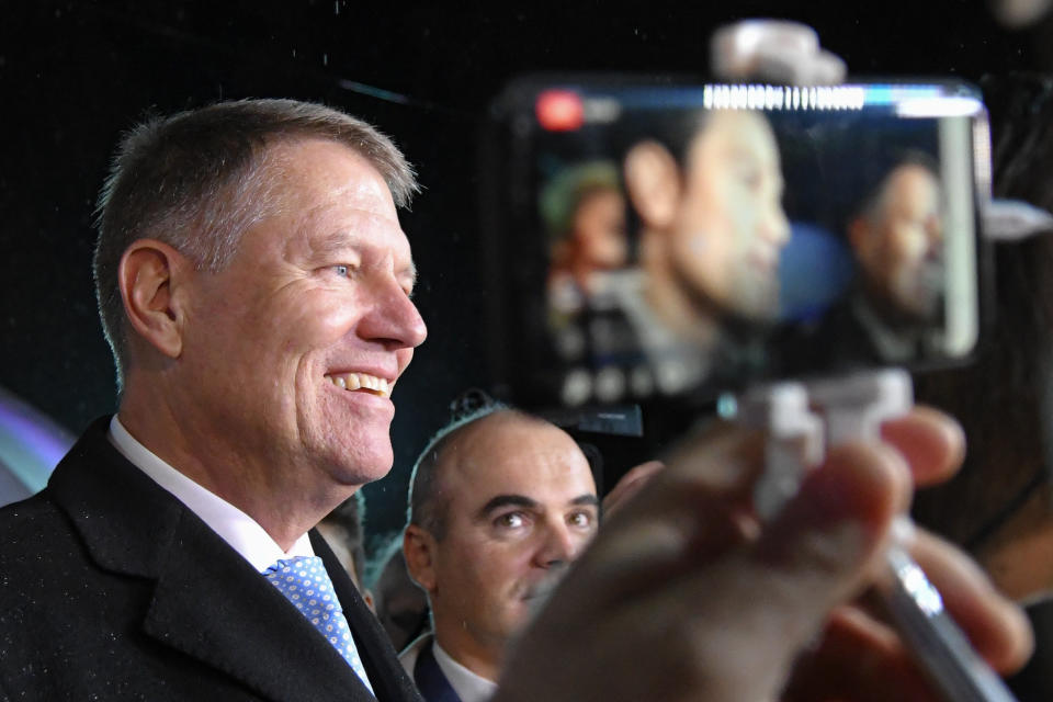 Romanian President Klaus Iohannis is surrounded by media after exit polls were published, in Bucharest, Romania, Sunday, Nov. 24, 2019. An exit poll by the IRES independent think tank showed Iohannis getting 66.5 % of the votes, with 33.5% for Social Democratic Party leader Viorica Dancila, a former prime minister. (AP Photo/Andreea Alexandru)