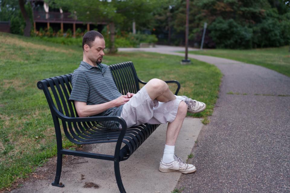 Jay Priebe scrolls through his phone at a park in his Twin Cities neighborhood.