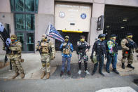 FILE - In this Jan. 18, 2021, file photo, men wearing Hawaiian shirts associated with the boogaloo movement stand on a sidewalk in Richmond, Va. People following the anti-government movement, which promotes violence and a second U.S. civil war, have been showing up at protests across the nation armed and wearing tactical gear. But the boogaloo movement has also adopted an unlikely public and online symbol: Hawaiian print shirts. (AP Photo/John C. Clark, File)